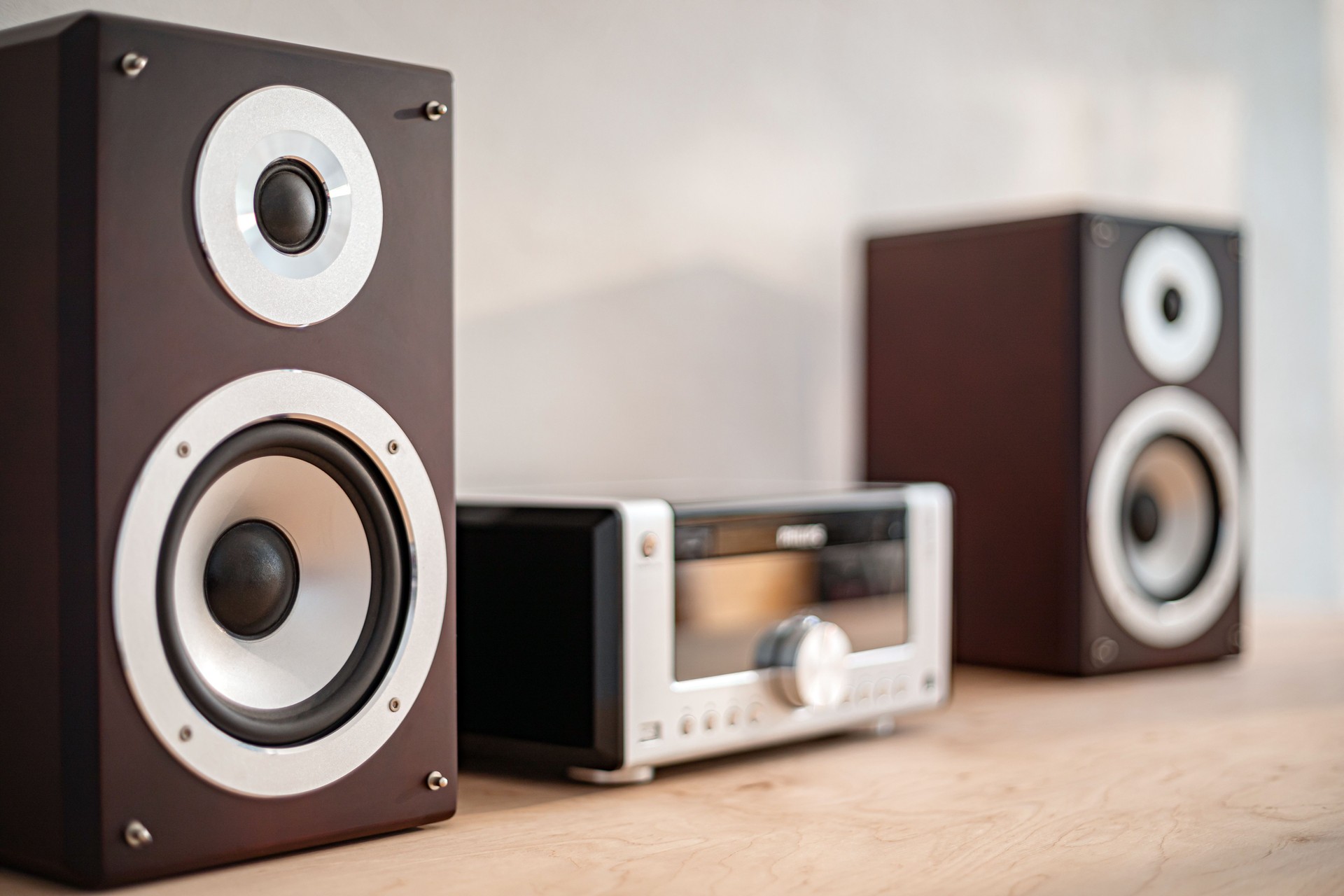 Stylish bookshelf speakers and a radio receiver arranged neatly on a wooden surface in a cozy interior setting