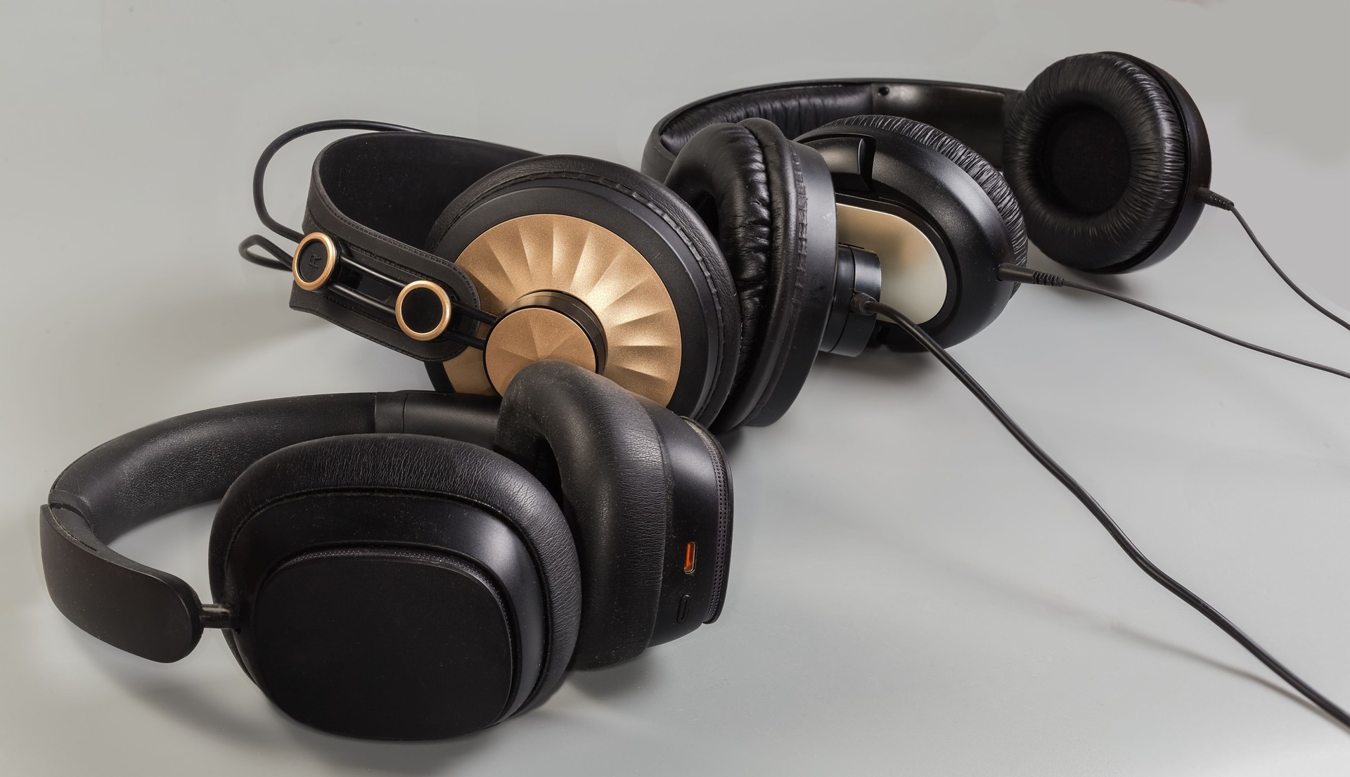 Various wired and wireless full size headphones on gray background