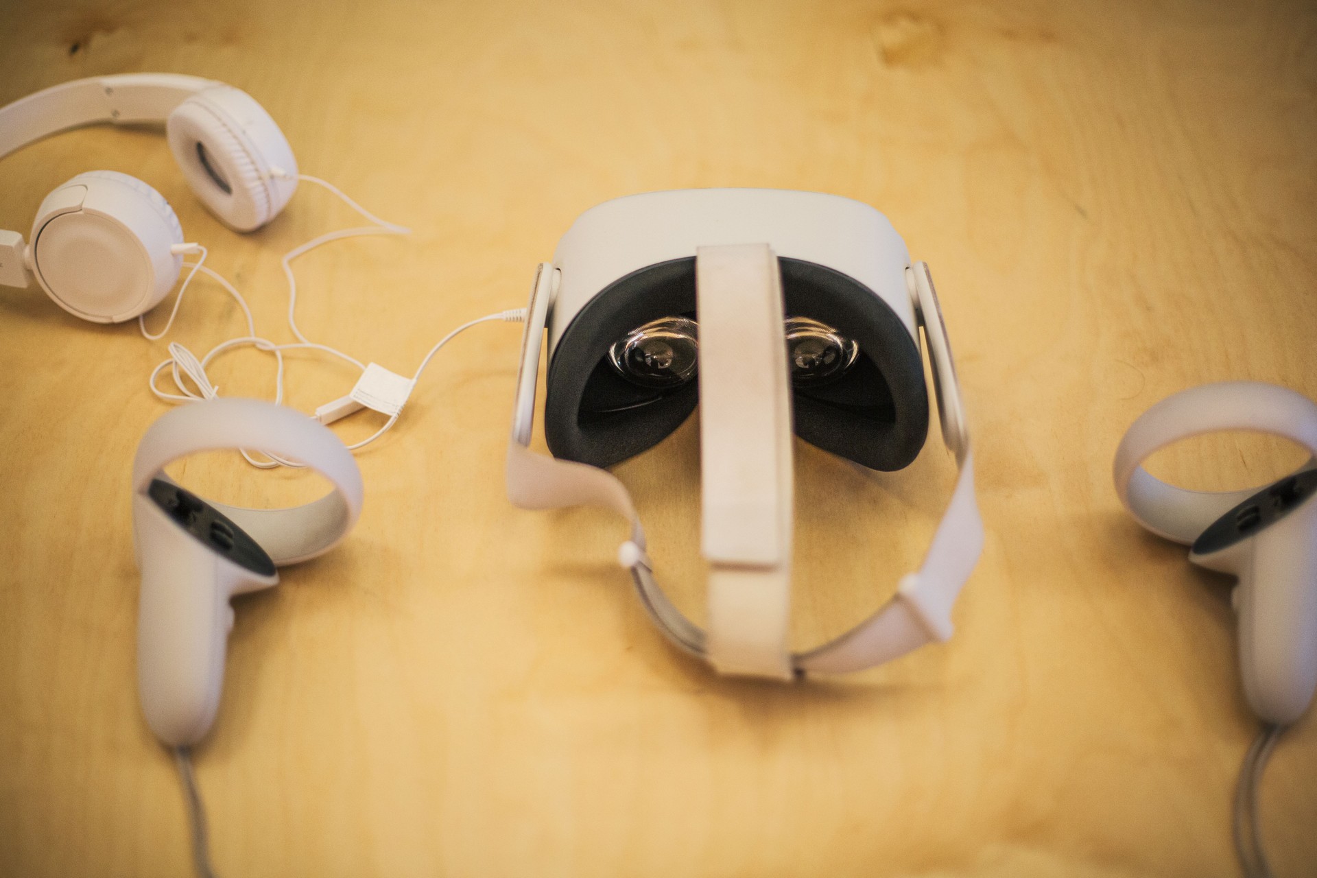 Virtual reality headset, controllers, and headphones resting on wooden table